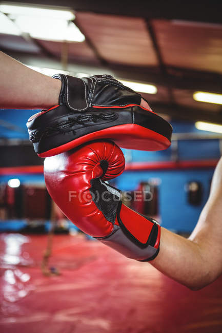 Hands of female boxer practicing with trainer at fitness studio — Stock Photo