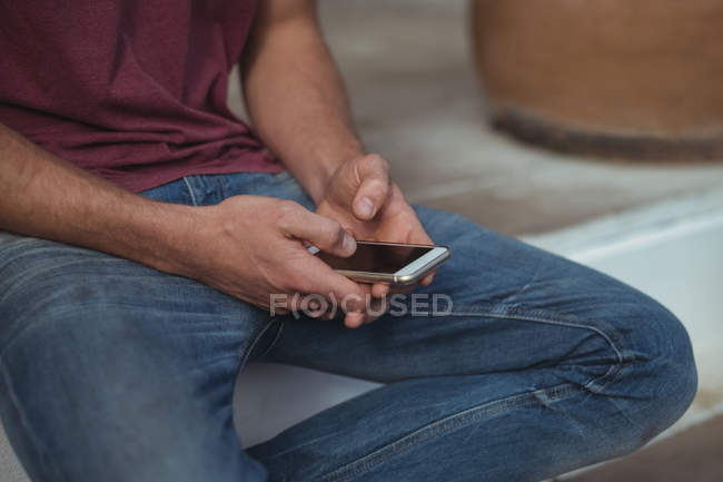 Средняя часть человека сидит и использует мобильный телефон — стоковое фото