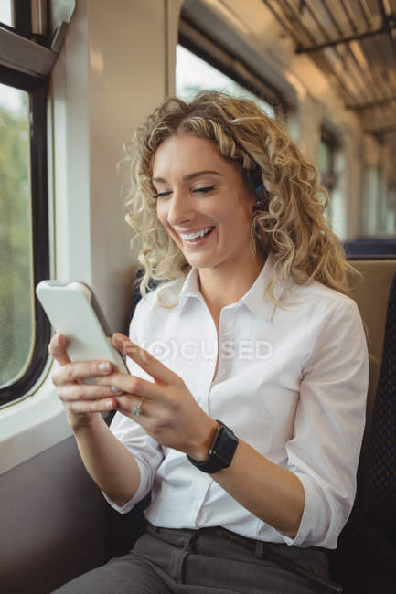 Alegre mujer de negocios mensajes de texto con teléfono inteligente mientras viaja - foto de stock