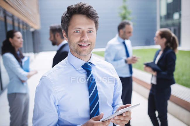 Portrait of a confident businessman holding digital tablet outside office building — Stock Photo