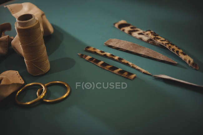 Pezzi di pelle e rocchetto di filo sul tavolo in officina — Foto stock