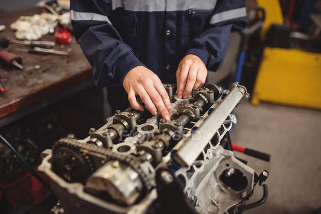 Meados de seção do mecânico fêmea verificando um carro peças na garagem de reparação — Fotografia de Stock