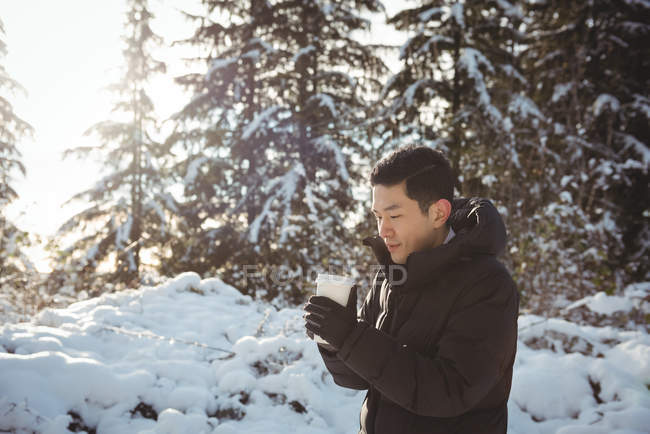 Homme en vêtements chauds tenant tasse de café pendant l'hiver — Photo de stock