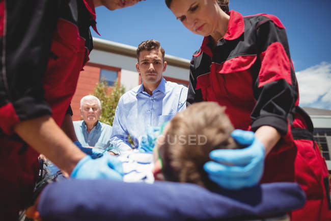Les ambulanciers examinent un garçon blessé dans la rue — Photo de stock