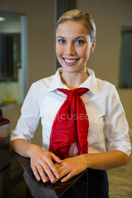 Portrait of smiling female staff standing at check in desk — Stock Photo