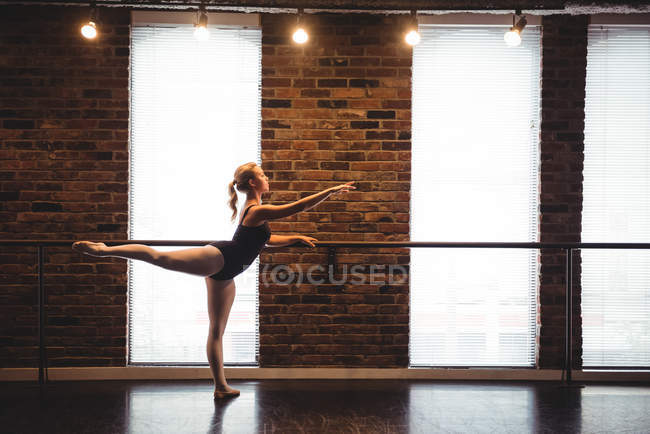 Bailarina practicando danza de ballet en bar en estudio de ballet - foto de stock