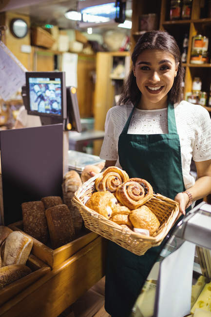 Жіночий персонал тримає круасан у плетеному кошику на лічильнику хліба в супермаркеті — стокове фото