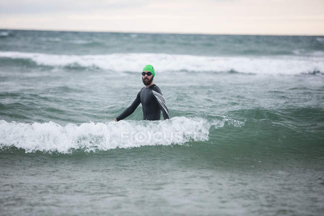 Atleta masculino en traje de neopreno de pie en el mar - foto de stock