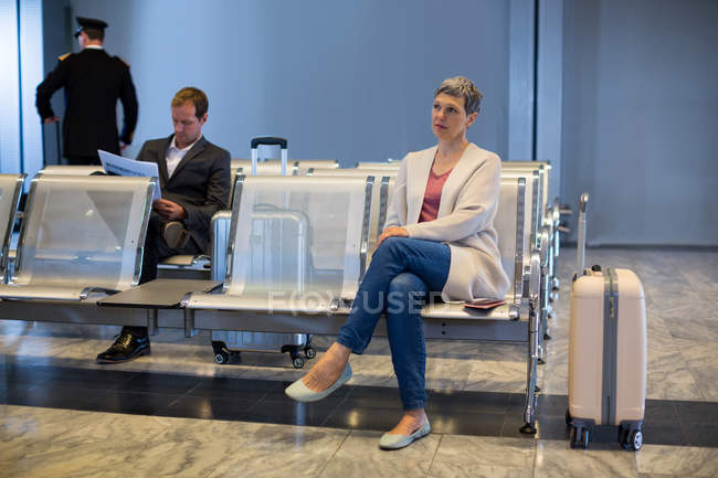 Mulher sentada na cadeira na área de espera no terminal do aeroporto — Fotografia de Stock