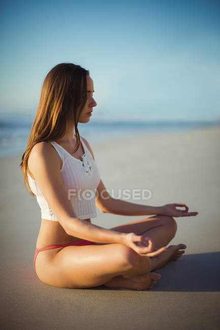 Schöne Frau, die an einem sonnigen Tag Yoga am Strand macht — Stockfoto