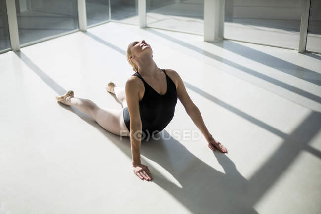 Bailarina esticando-se no chão no estúdio — Fotografia de Stock
