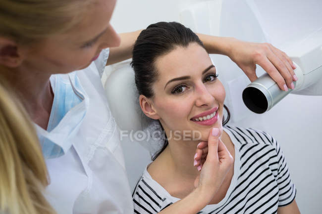 Dentista tomando radiografías de dientes de paciente femenino en clínica - foto de stock