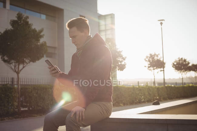 Чоловік керівник, використовуючи смартфон на вулиці перед офісною будівлею — стокове фото