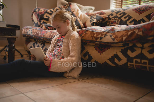 Дівчина сидить на підлозі і використовує цифровий планшет у вітальні вдома — стокове фото