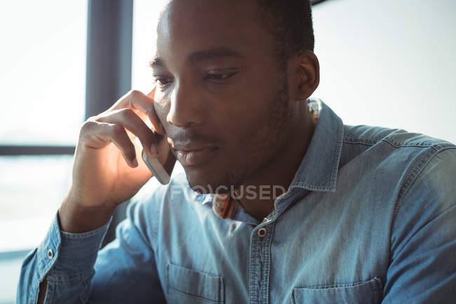 Business executive talking on mobile phone in office — Stock Photo