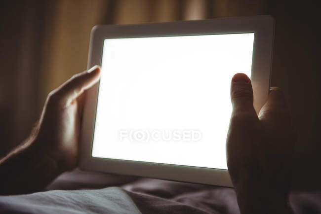 Close-up of male hands using digital tablet in bedroom at home — Stock Photo