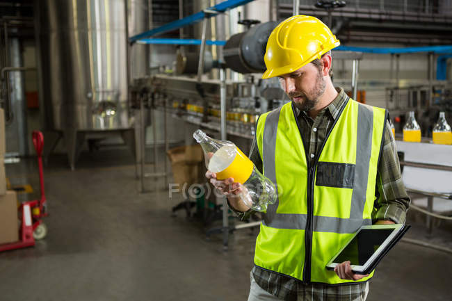 Trabalhador masculino confiante inspecionando garrafas na fábrica de suco — Fotografia de Stock