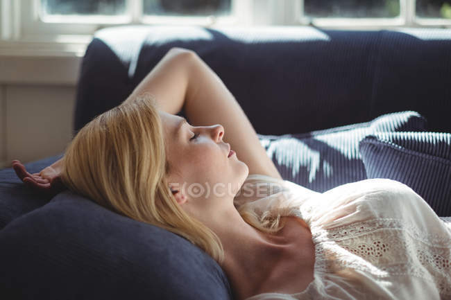 Mulher bonita relaxando no sofá na sala de estar em casa — Fotografia de Stock