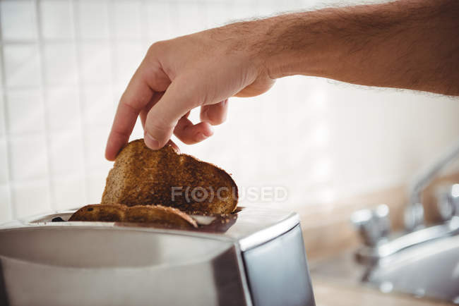 Gros plan sur l'homme grillant du pain dans la cuisine à la maison — Photo de stock