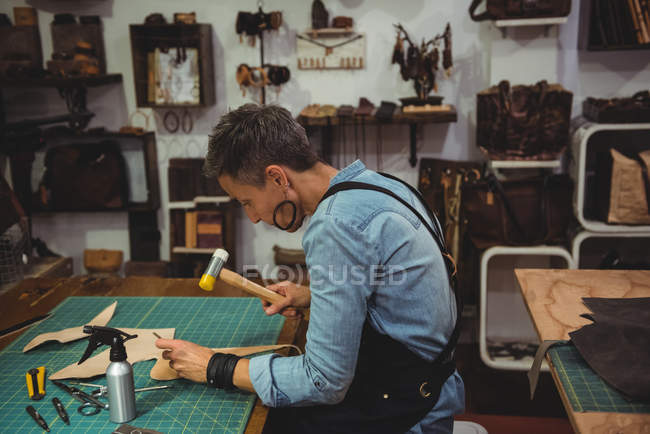 Madura artesana martillando cuero en taller - foto de stock