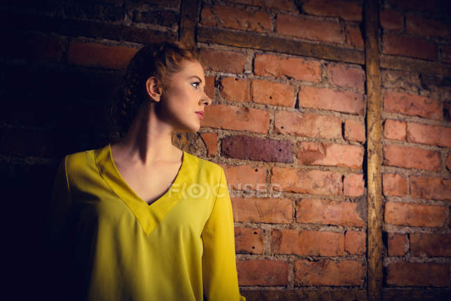 Mulher bonita de pé contra a parede de tijolo — Fotografia de Stock
