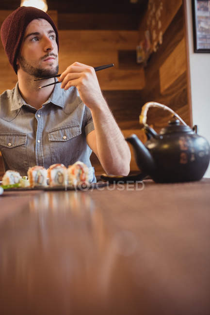 Homme réfléchi mangeant des sushis au restaurant — Photo de stock