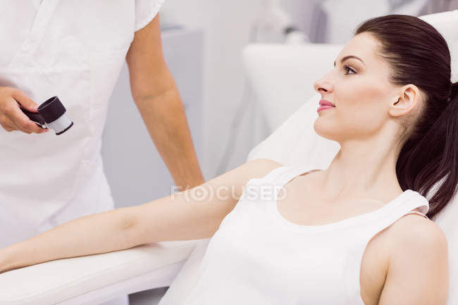 Dermatologist examining skin of patient with dermatoscope in clinic — Stock Photo
