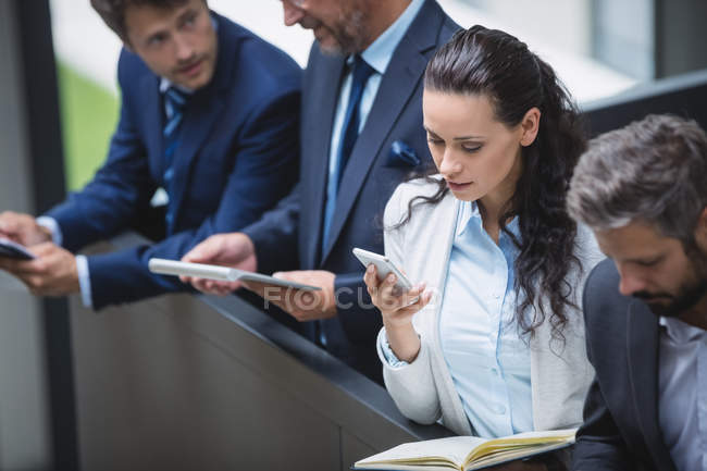 Empresários usando celular e tablet digital no escritório — Fotografia de Stock