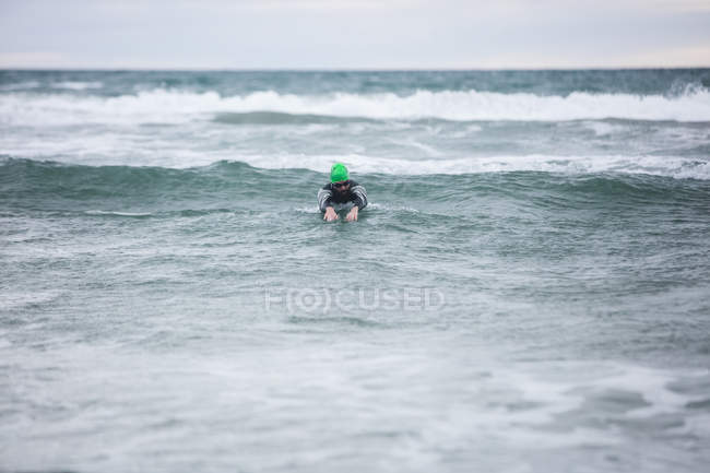 Спортсмен в гидрокостюме плавает в морской воде — стоковое фото