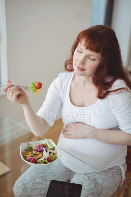 Donna incinta che mangia insalata a casa — Foto stock