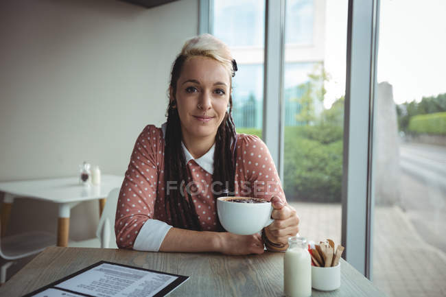Портрет улыбающейся женщины, пьющей кофе в кафе — стоковое фото