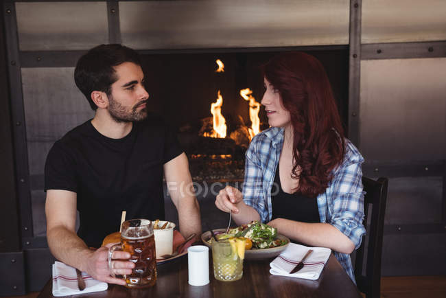 Друзья общаются во время еды в баре — стоковое фото