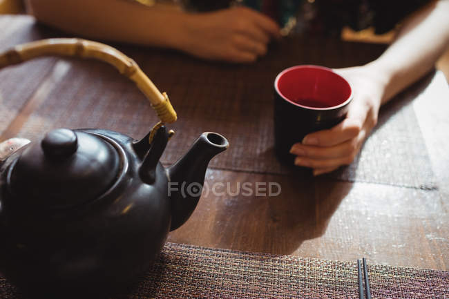 Mid section of woman having tea in restaurant — Stock Photo