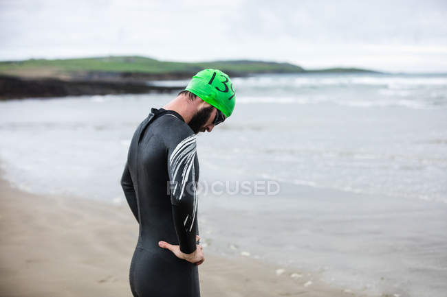 Atleta cansado se inclinando para recuperar o fôlego na praia — Fotografia de Stock