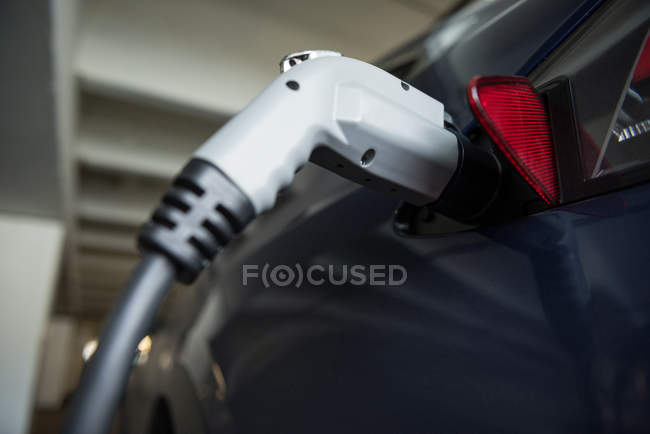 Close-up de carregamento de carro com carregador de carro elétrico na estação de carregamento — Fotografia de Stock