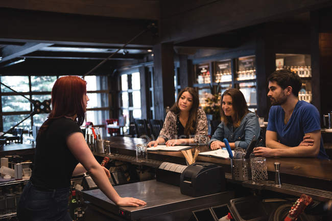 Bartender interacting with customers at bar counter — Stock Photo