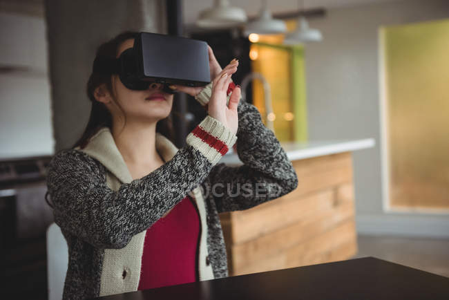 Женщина, использующая гарнитуру виртуальной реальности в гостиной дома — стоковое фото