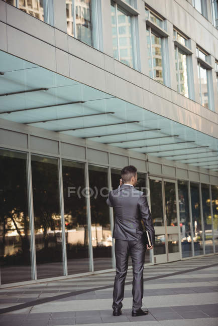 Rear view of businessman with a diary talking on phone in the office campus — Stock Photo