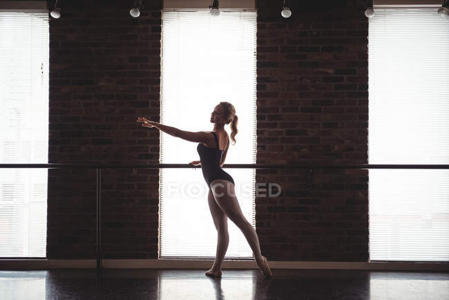 Ballerina übt Ballettschritt an der Barre im Ballettstudio — Stockfoto