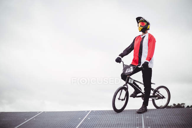 Ciclista de pie con bicicleta BMX en rampa de salida en skatepark - foto de stock