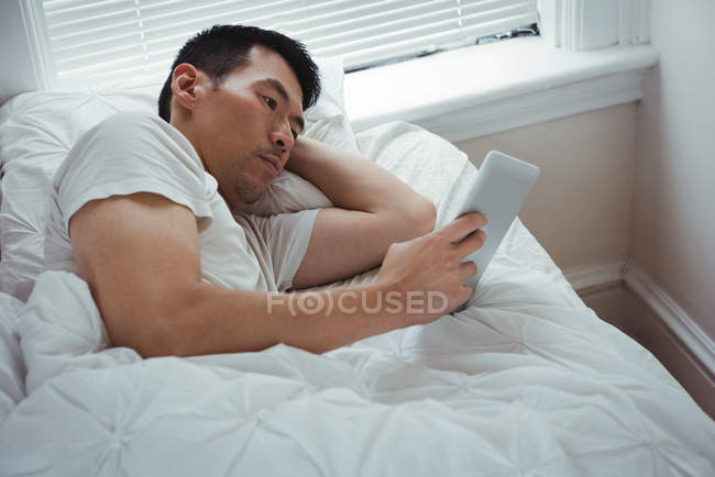 Людина, використовуючи цифровий планшетний в спальні в домашніх умовах — стокове фото