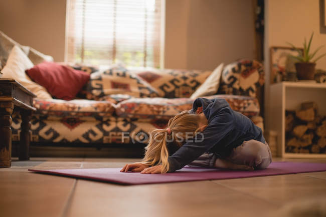 Menina realizando ioga na sala de estar em casa — Fotografia de Stock