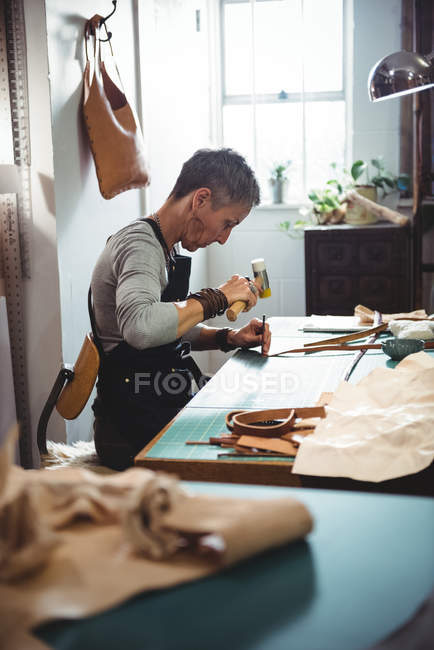 Reife Handwerkerin hämmert in Werkstatt auf Leder — Stockfoto