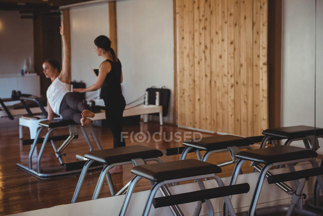 Instructor helping woman practicing pilates in fitness studio — Stock Photo