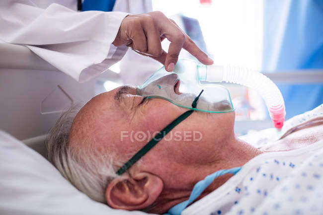 Mano de doctora poniendo máscara de oxígeno en la cara del paciente en el hospital - foto de stock