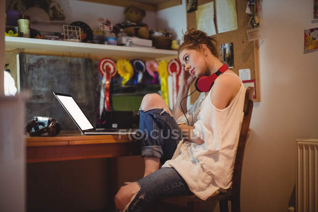Femme réfléchie utilisant un ordinateur portable à la maison — Photo de stock