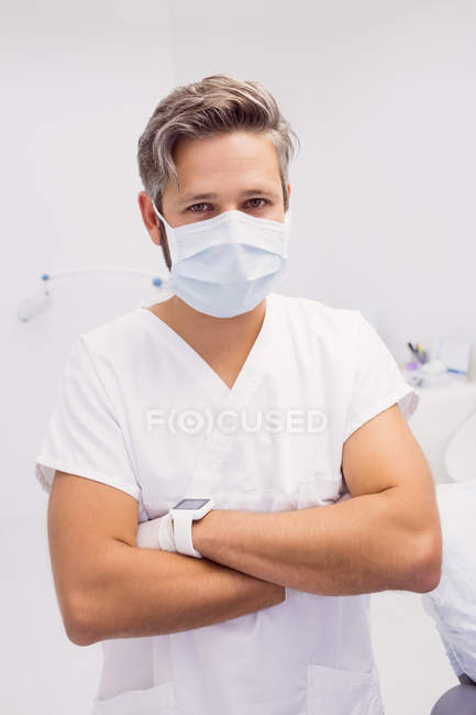 Dentista de pé com os braços cruzados na clínica — Fotografia de Stock