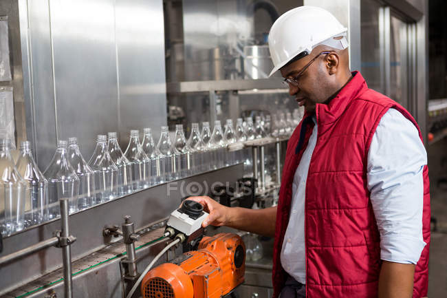 Confident male employee operating machine in juice factory — Stock Photo