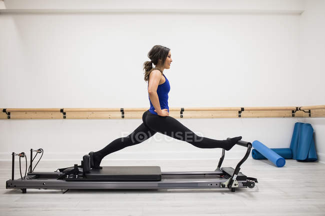 Mulher se alongando no equipamento reformador no ginásio — Fotografia de Stock