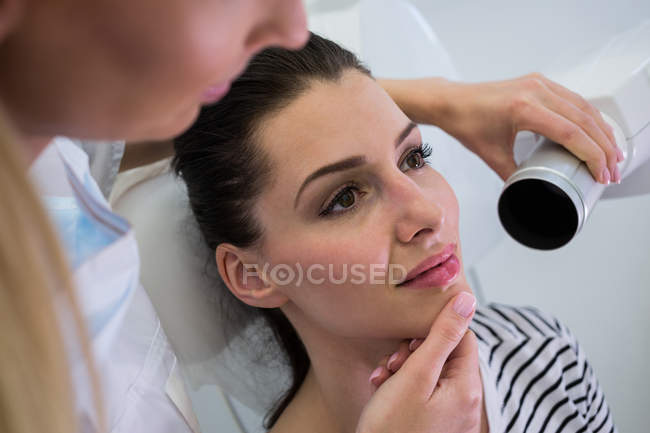 Dentista tomando radiografías de dientes de paciente femenino en clínica - foto de stock